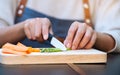 A woman cutting and chopping asparagus and carrot by knife on wooden board Royalty Free Stock Photo