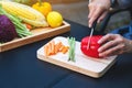 a woman cutting and chopping red bell pepers by knife on wooden board with mixed vegetables in a tray Royalty Free Stock Photo