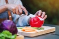 A woman cutting and chopping red bell pepers by knife on wooden board with mixed vegetables in a tray Royalty Free Stock Photo