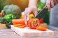 A woman cutting and chopping tomato by knife on wooden board Royalty Free Stock Photo