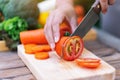A woman cutting and chopping tomato by knife on wooden board Royalty Free Stock Photo