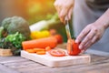 A woman cutting and chopping tomato by knife on wooden board Royalty Free Stock Photo