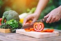 A woman cutting and chopping tomato by knife on wooden board Royalty Free Stock Photo