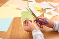 Woman cutting color paper with scissors at wooden table, closeup Royalty Free Stock Photo