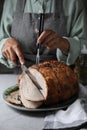 Woman cutting delicious baked ham at wooden table, closeup