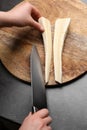 Woman cutting delicious fresh ripe parsnip at black table, top view