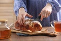 Woman cutting delicious yeast dough cake at wooden table, closeup