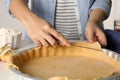 Woman cutting dough leftovers for traditional English apple pie in baking dish at table, closeup