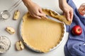 Woman cutting dough leftovers for traditional English apple pie in baking dish at white table, top view