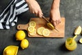 Woman cutting fresh lemon for juice on grey table Royalty Free Stock Photo