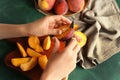 Woman cutting fresh peaches at green table Royalty Free Stock Photo