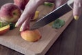 A woman cutting fresh peaches on a wooden cutting board, close up