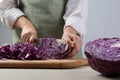 Woman cutting fresh radicchio cabbage on board at wooden table, closeup