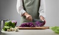 Woman cutting fresh radicchio cabbage on board at wooden table, closeup