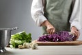 Woman cutting fresh radicchio cabbage on board at wooden table, closeup