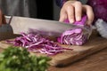 Woman cutting fresh red cabbage at wooden table, closeup Royalty Free Stock Photo