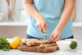 Woman cutting ginger on table in kitchen Royalty Free Stock Photo