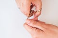 The woman is cutting her nails with small scissors by herself in close up photo on white background. View from above. Manicure at Royalty Free Stock Photo