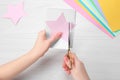 Woman cutting paper with scissors at white wooden table, top view Royalty Free Stock Photo