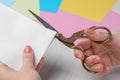 Woman cutting paper with scissors at white wooden table, closeup Royalty Free Stock Photo