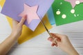 Woman cutting paper star with scissors at white wooden table, top view Royalty Free Stock Photo