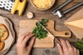 Woman cutting parsley for garlic bread at table, top view