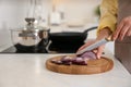 Woman cutting red onion into slices at table in kitchen, closeup Royalty Free Stock Photo