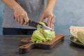 Woman cutting ripe cabbage at table