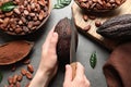Woman cutting ripe cocoa pod over grey table with products Royalty Free Stock Photo