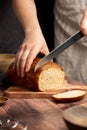 Woman cutting sourdough white loaf bread on wooden board. Homemade healthy cooking concept. Royalty Free Stock Photo