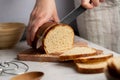 Woman cutting sourdough white loaf bread on wooden board. Homemade healthy cooking concept. Royalty Free Stock Photo