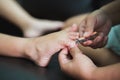 Woman cutting toenails to her daughter on dark brown sofa Royalty Free Stock Photo