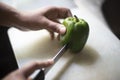 Woman cutting whole green capsicum with a knife on a chopping board in an Indian kitchen Royalty Free Stock Photo