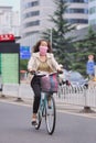 Woman cycles with mouth cloth as protection, Kunming, China