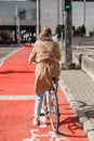 woman cycling along red bike lane road in city