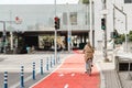 woman cycling along red bike lane road in city