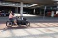 A woman cycling with kids on a cargo bike at the Amsterdam Central Train Station, Netherlands