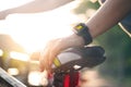 Woman cyclist hand with smart watch on saddle bicycle at summer trail
