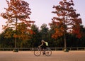 Woman cyclist riding her bike in a londons park, between two red leaf trees