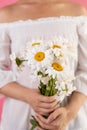 close up of woman holding bouquet of chamomile flowers on pink background. Royalty Free Stock Photo