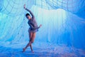 A woman dances in a room with white drapes made of thin airy fabric, illuminated by blue spotlights Royalty Free Stock Photo