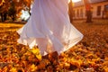 Woman dancing in autumn forestamoung orange and yellow maple leaves. Lady wearing stylish white skirt