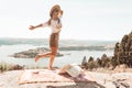 Woman dancing high on a rocky outcrop with views over waterways