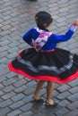 Woman dancing with typical Cuzco clothes with hats at the Inti Raymi Sun Festival, overhead view with Peru cobblestones background