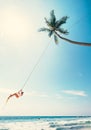 Woman dangles on tropical palm tree swing over ocean waves Royalty Free Stock Photo