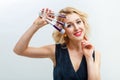 Woman in a dark blue dress is looking at the camera on a white background. Makeup artist holds brushes near the face Royalty Free Stock Photo