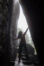 Woman in the dark cave with flaslight. back view. scenist girl between stones wall. Royalty Free Stock Photo