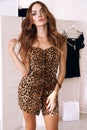 Woman with dark hair in elegant dress with leopard print posing in changing room Royalty Free Stock Photo
