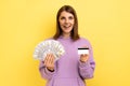 Woman with dark hair holding fan of dollars banknotes and credit card, earning money, banking. Royalty Free Stock Photo