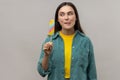 Woman with dark hair holding multicolored ice cream in hands, feels hungry, wants to taste dessert.